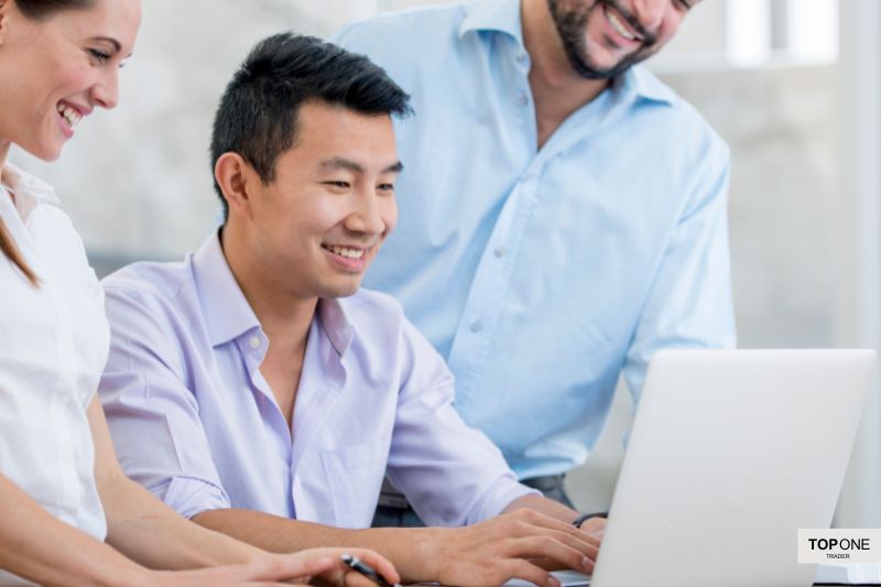 Group of traders discussing forex trading strategies on a laptop