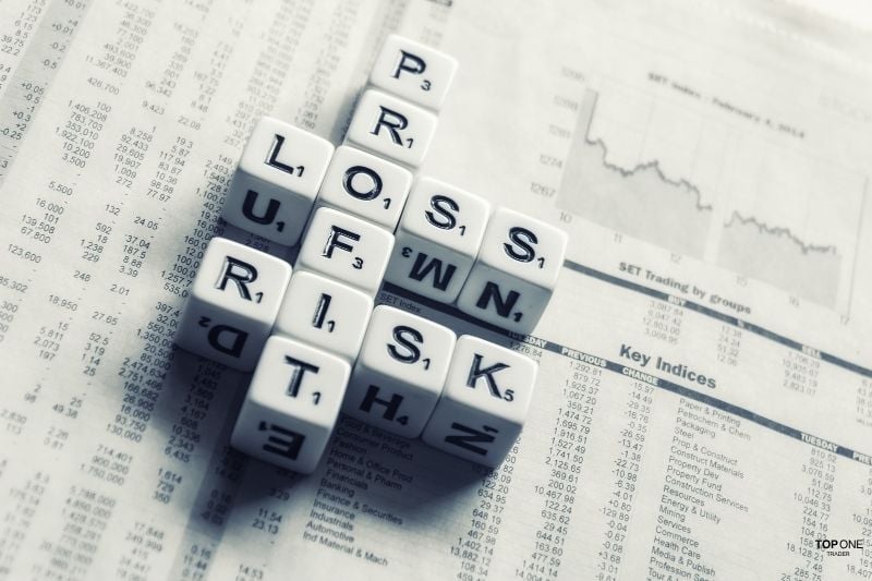 Scrabble cubes spelling "profit," "loss," and "risk" over financial data, symbolising PnL in trading.